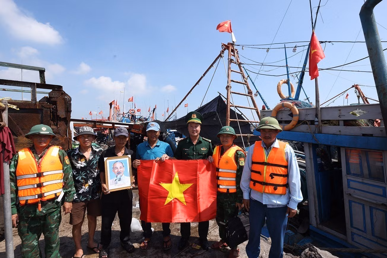 Bộ đội Biên phòng Hải Hoà tặng cờ Tổ quốc cho chủ tàu cá Nguyễn Văn Chiến, chuẩn bị ra khơi khai thác thuỷ sản, tại cảng cá Lạch Bạng, phường Hải Bình, tỉnh Thanh Hóa.