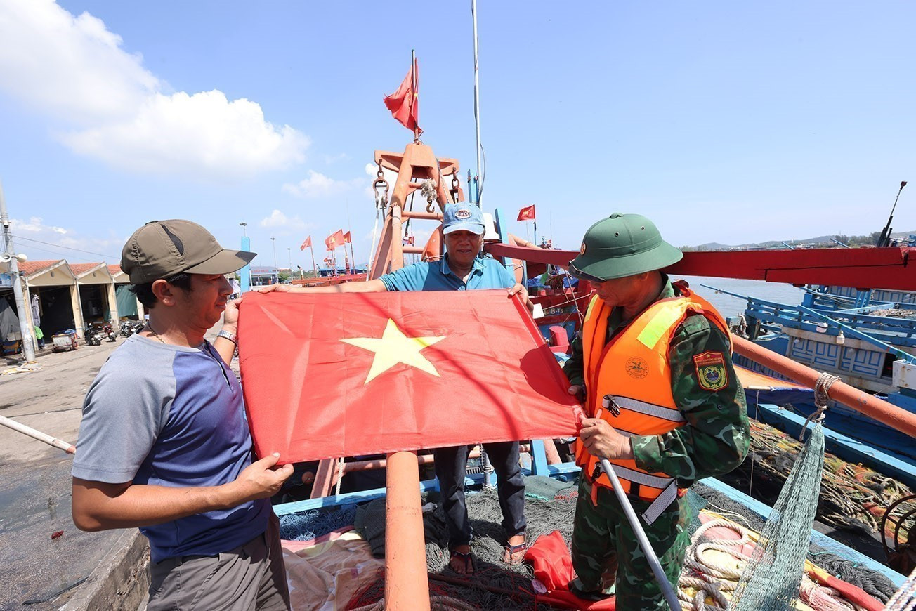 Bộ đội Biên phòng Hải Hoà tặng cờ Tổ quốc cho chủ tàu cá Nguyễn Văn Chiến, chuẩn bị ra khơi khai thác thuỷ sản, tại cảng cá Lạch Bạng, phường Hải Bình, tỉnh Thanh Hóa. Bộ đội Biên phòng Hải Hoà tặng cờ Tổ quốc cho chủ tàu cá Nguyễn Văn Chiến, chuẩn bị ra khơi khai thác thuỷ sản, tại cảng cá Lạch Bạng, phường Hải Bình, tỉnh Thanh Hóa.