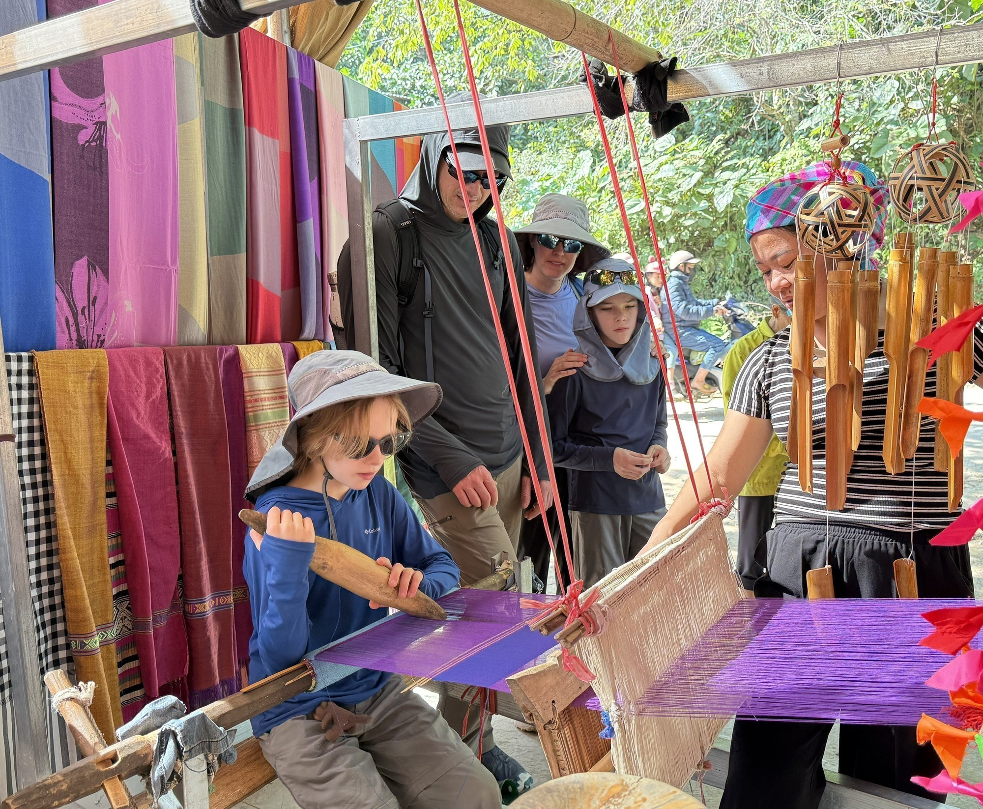 Du khách quốc tế thích thú khi được trải nghiệm quá trình dệt thổ cẩm của người dân tộc Thái.
