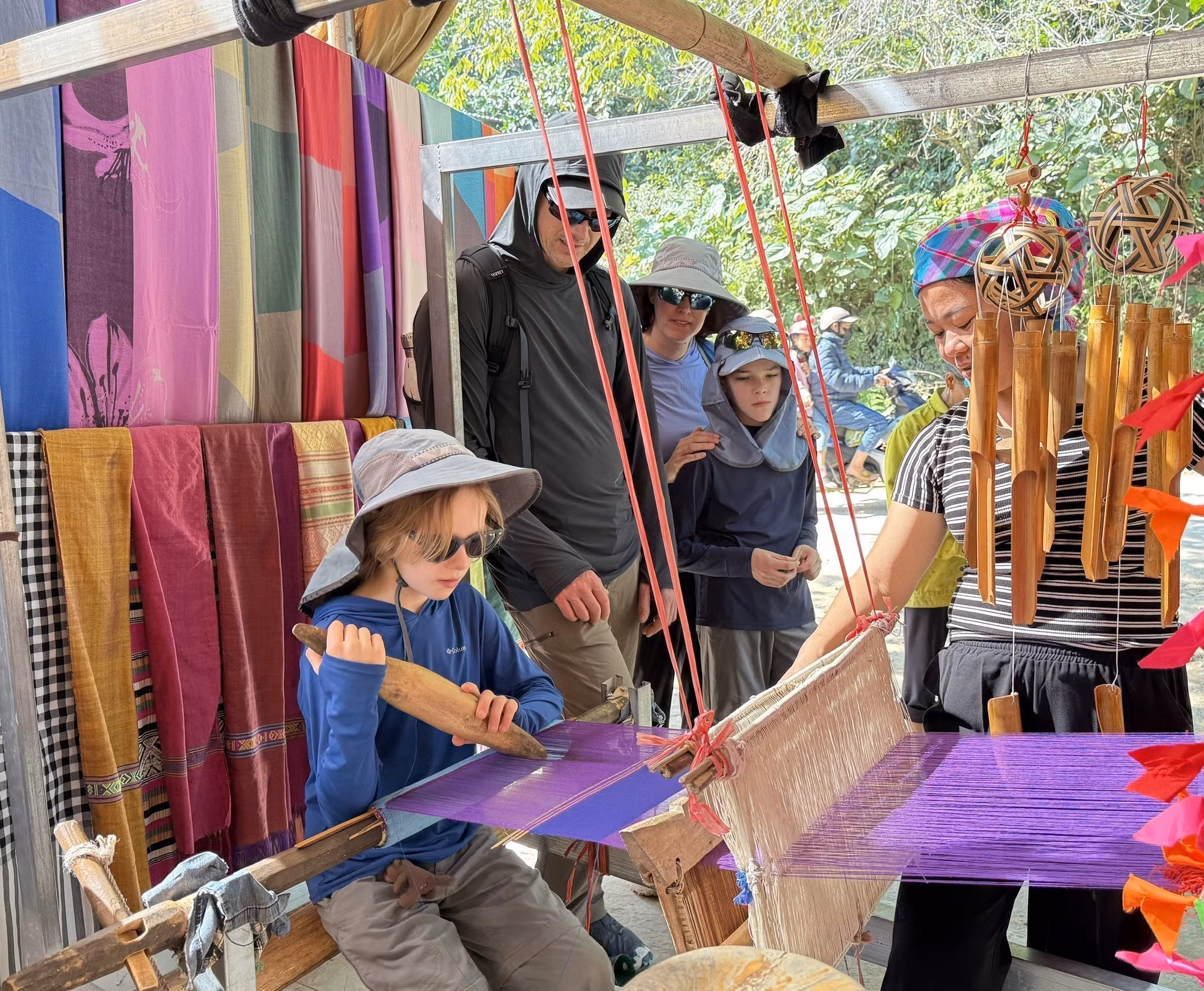 Du khách quốc tế thích thú khi được trải nghiệm quá trình dệt thổ cẩm của người dân tộc Thái.