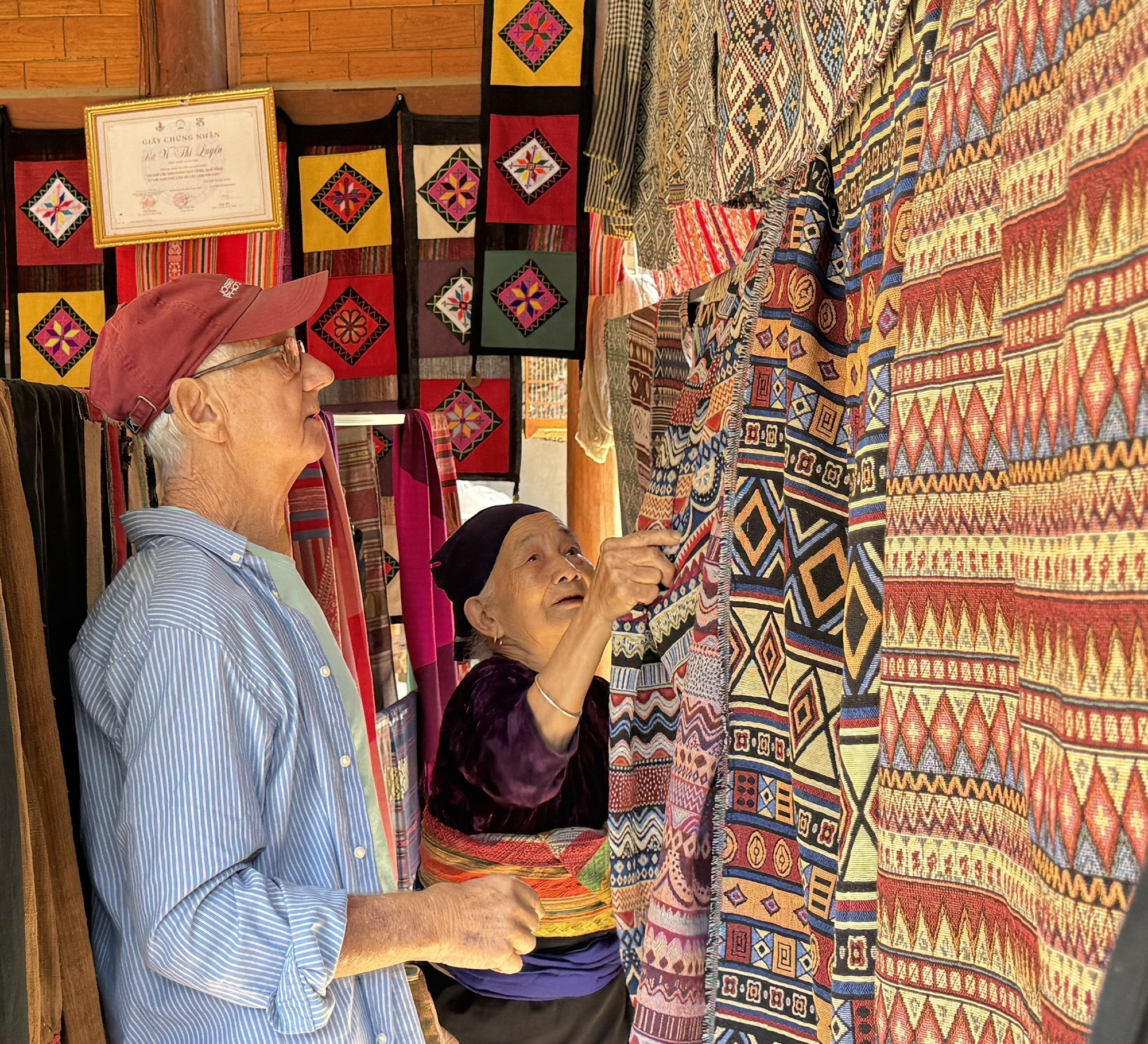 Ông Roistacher Bob (82 tuổi), du khách Mỹ, chọn mua sản phẩm thổ cẩm tại thôn Lặn Ngoài, xã Pù Luông.
