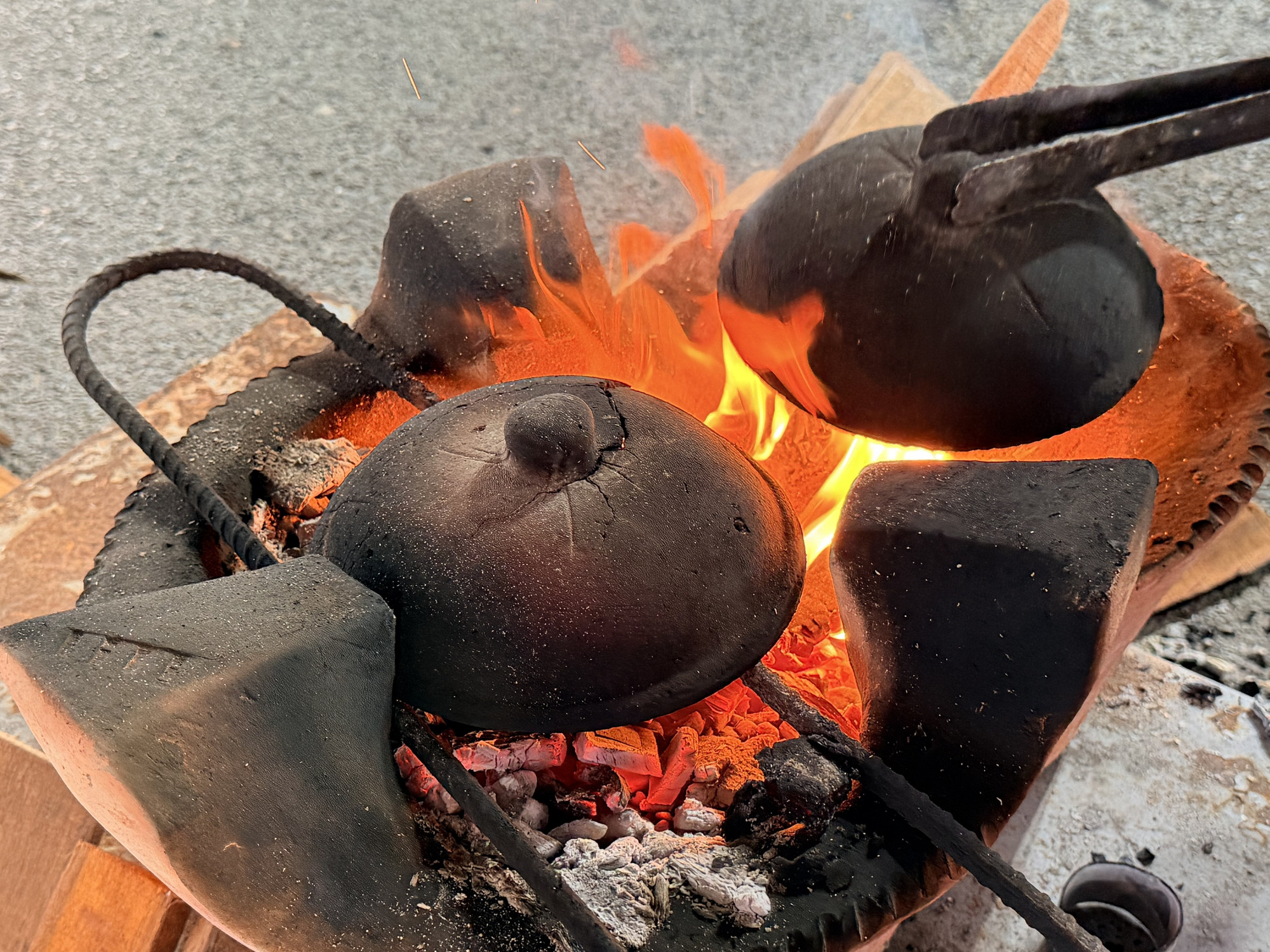 Để mặt bánh chín vàng đều, nghệ nhân hơ nóng nắp chảo trên bếp củi rồi nhanh tay đậy lên.