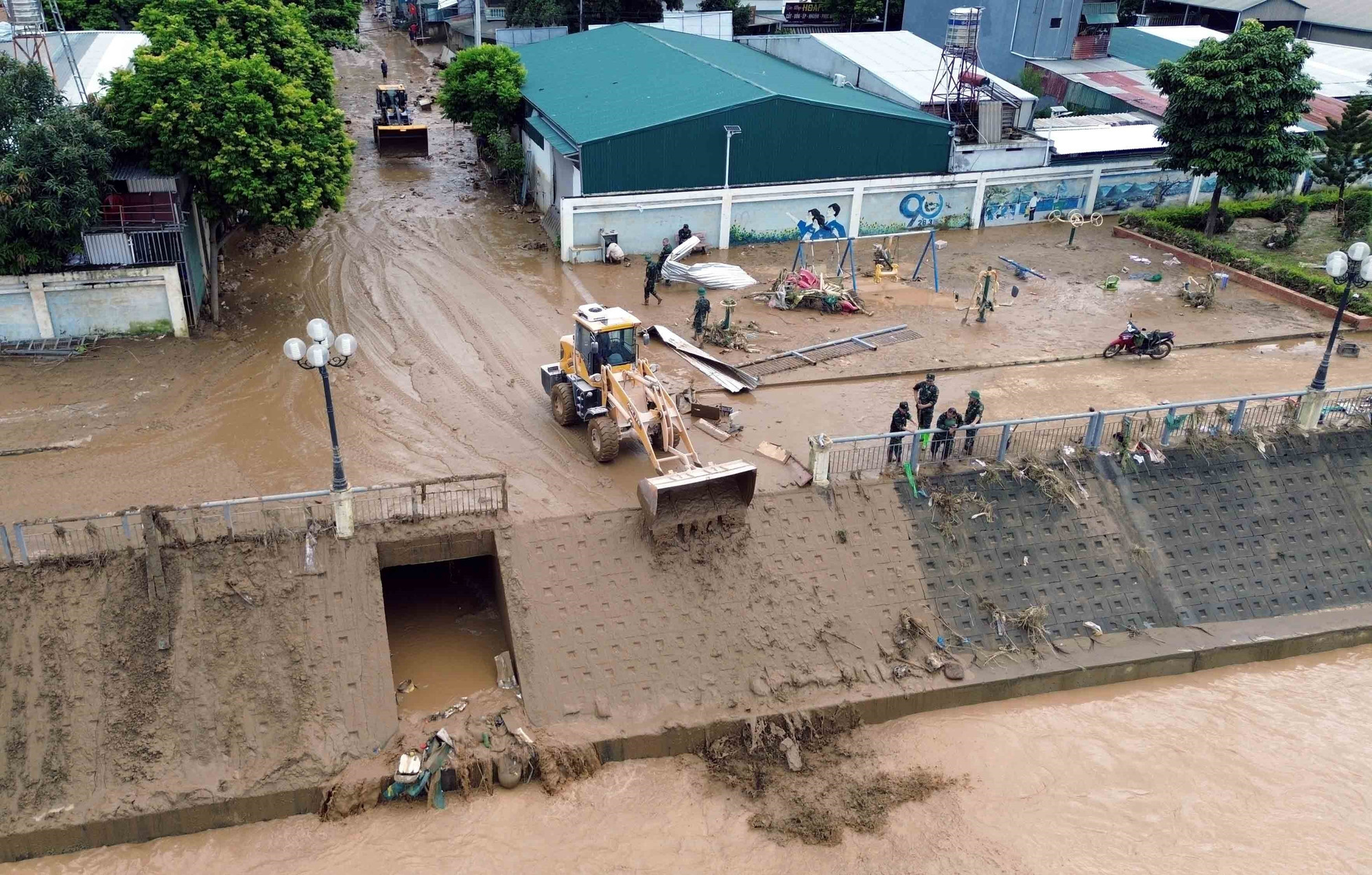 Máy xúc được huy động để hỗ trợ san gạt, thu gom bùn đất, cành cây, rác bị tràn về trong đợt lũ vừa qua tại xã Sông Mã. thien-tai-song-ma-son-la-7.jpg