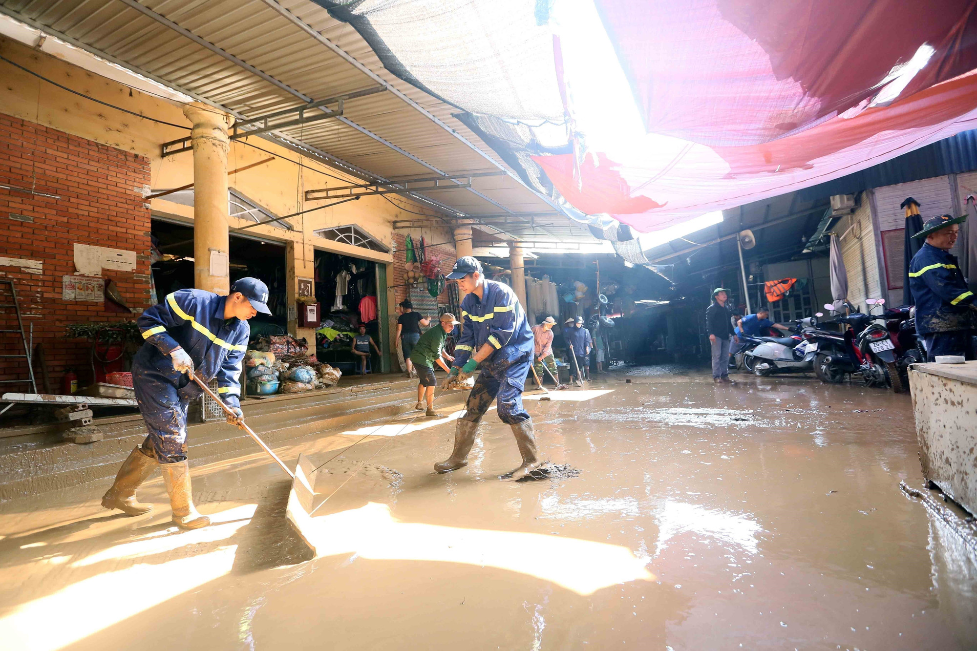 Hỗ trợ các hộ kinh doanh tại chợ Sông Mã thu gom bùn đất, cành cây, rác bị tràn về trong đợt lũ vừa qua. thien-tai-song-ma-son-la-4.jpg