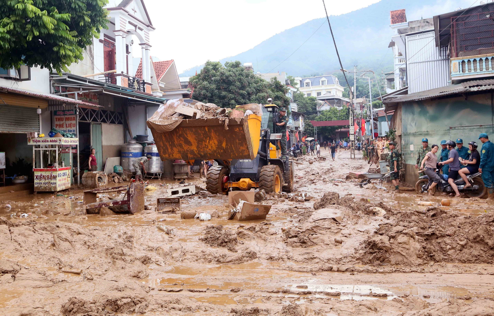 Máy xúc được huy động để hỗ trợ san gạt, thu gom bùn đất, cành cây, rác bị tràn về trong đợt lũ vừa qua tại xã Sông Mã. thien-tai-song-ma-son-la-2.jpg