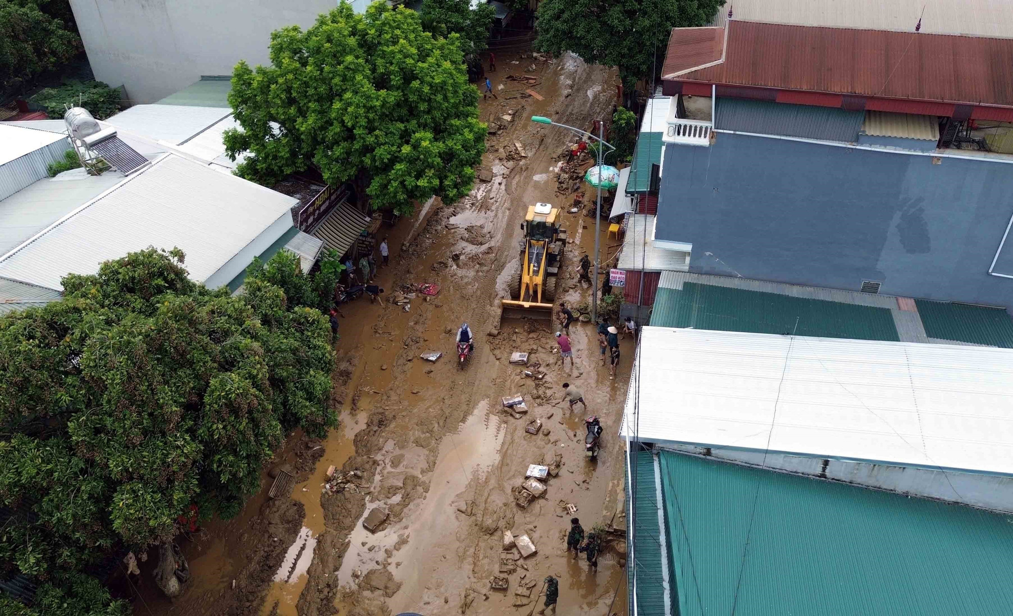 Máy xúc được huy động để hỗ trợ san gạt, thu gom bùn đất, cành cây, rác bị tràn về trong đợt lũ vừa qua tại xã Sông Mã. thien-tai-song-ma-son-la-8.jpg
