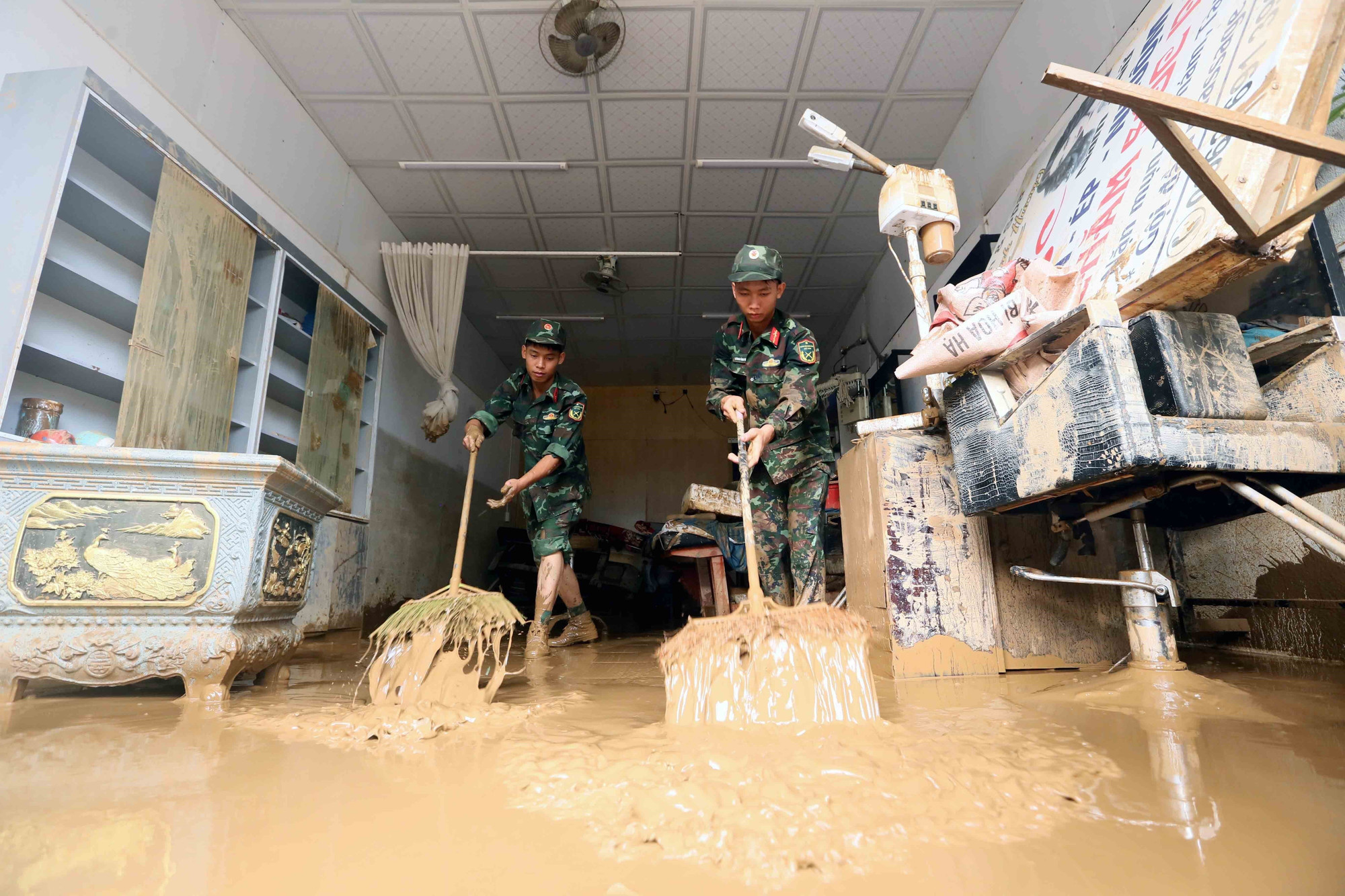 Lực lượng quân đội hỗ trợ người dân tổ 4, xã Sông Mã thu gom bùn đất, cành cây, rác bị tràn về trong đợt lũ vừa qua. thien-tai-song-ma-son-la-3.jpg