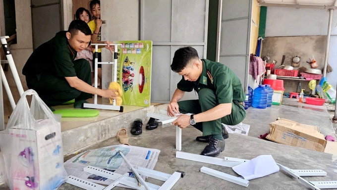 Cán bộ chiến sĩ Đồn Biên phòng Nhật Lệ chuẩn bị bàn ghế mới cùng cặp sách, đồ dùng học tập cho học sinh được đơn vị đỡ đầu, hỗ trợ. Ảnh: TTXVN phát con-nuoi-5925-12.jpg