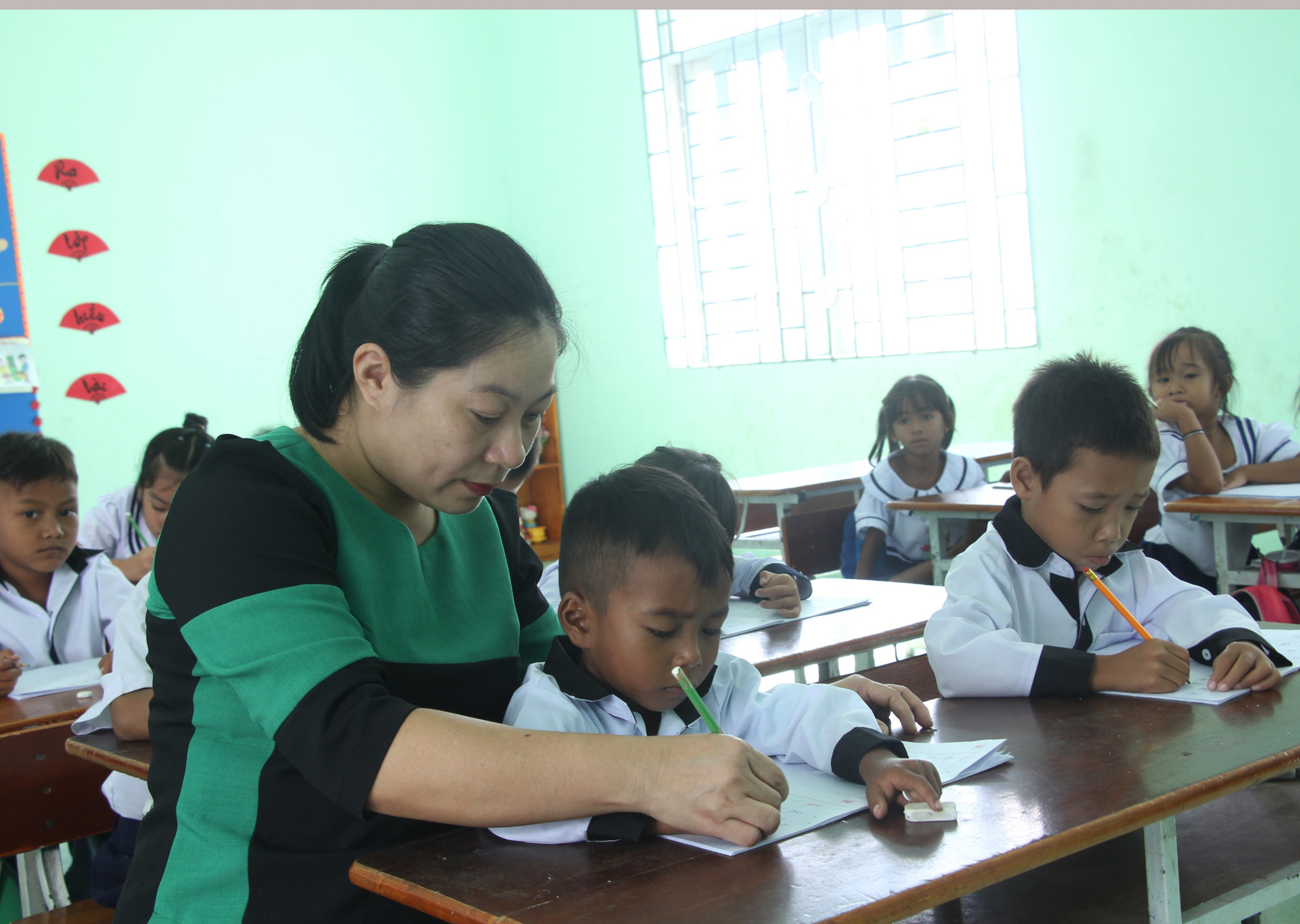 Cô Bùi Thị Hương, Trường Tiểu học Phước Thắng, xã Bác Ái, tỉnh Khánh Hòa cầm bút và tay của trẻ để hướng dẫn trẻ cách tập viết chữ tiếng Việt. Cô Bùi Thị Hương, Trường Tiểu học Phước Thắng, xã Bác Ái, tỉnh Khánh Hòa cầm bút và tay của trẻ để hướng dẫn trẻ cách tập viết chữ tiếng Việt.