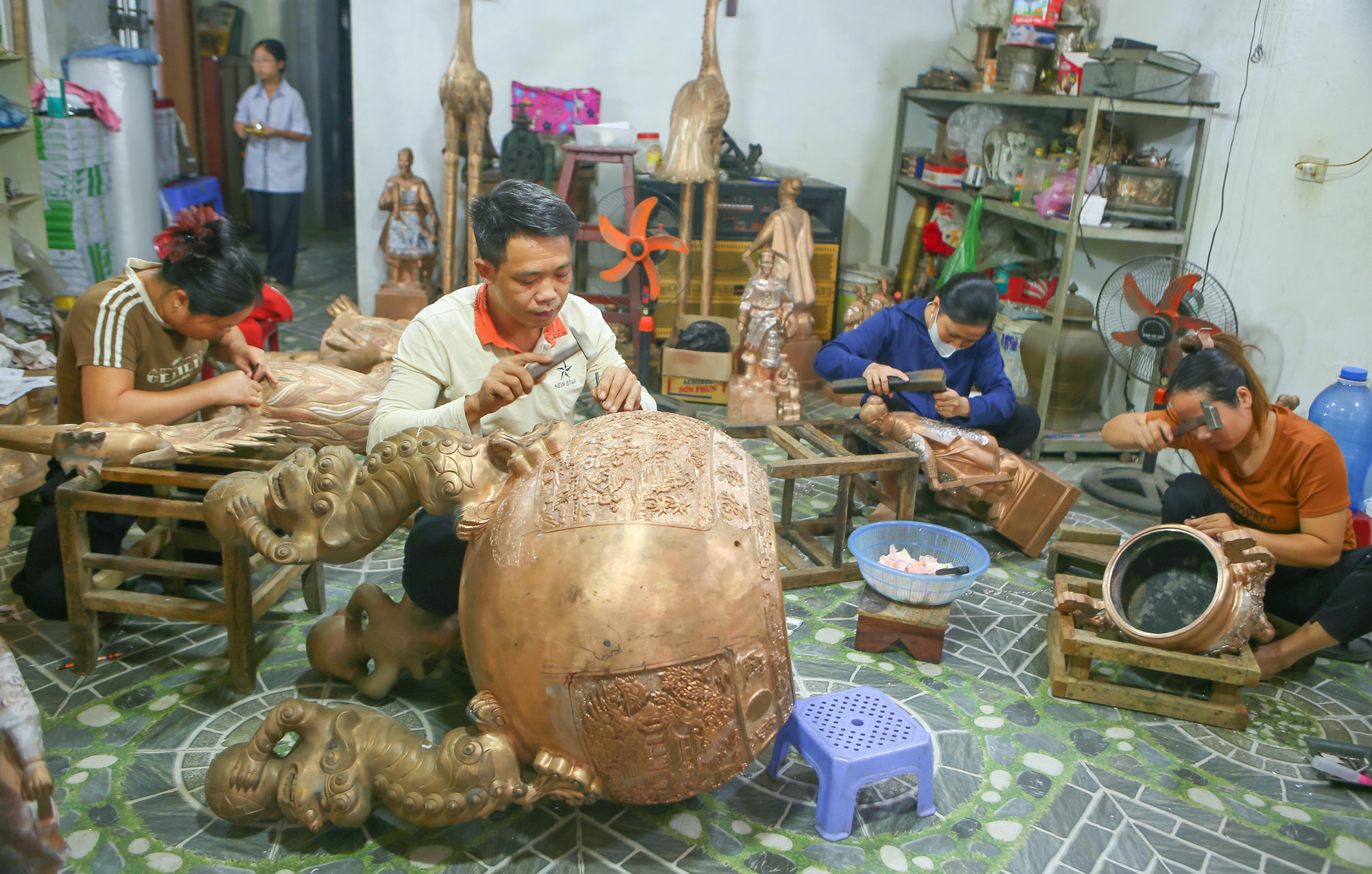 Những người thợ tại làng nghề đúc đồng Ý Yên chạm khắc hoàn thiện sản phẩm.