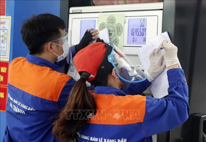 Nhân viên cửa hàng xăng dầu điều chỉnh giá bán. Ảnh: Trần Việt - TTXVN