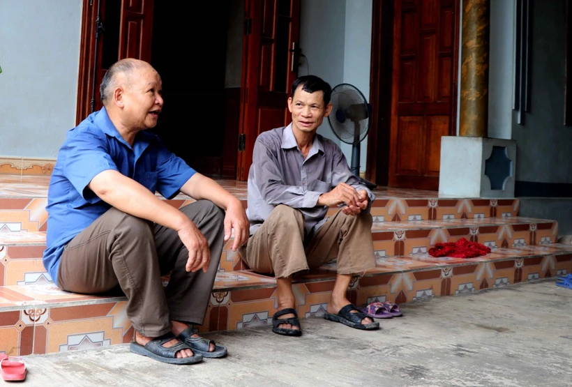 Ông Lý Văn Dau (bên trái) vận động người dân thực hiện tốt đường lối chủ trương của Đảng, pháp luật của Nhà nước. Ảnh: Quang Cường – TTXVN