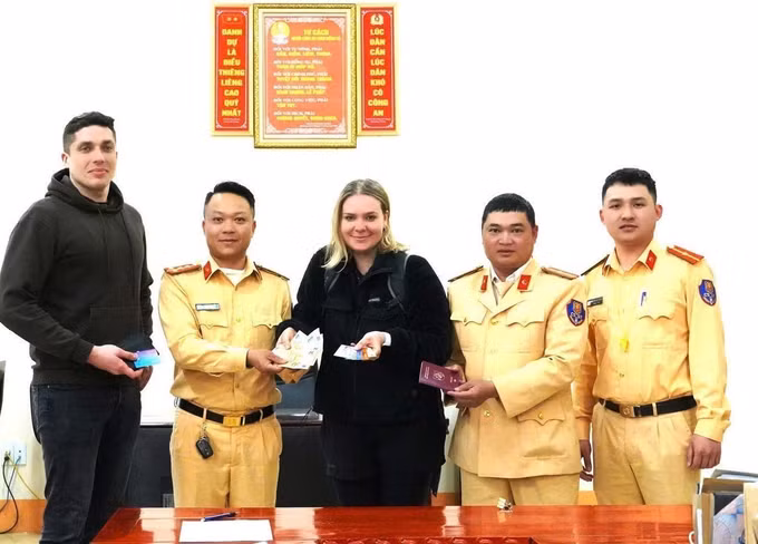 Cán bộ, chiến sĩ Tổ công tác số 10, Đội 4, Phòng Cảnh sát Giao thông, Công an tỉnh Hà Giang trao trả tài sản bị rơi cho chị Zukiene, quốc tịch Litva. Ảnh: TTXVN phát
