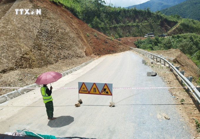 Đơn vị quản lý tuyến đường đã cử người chốt trực, căng dây, cắm biển báo hiệu. Ảnh: TTXVN phát vna_potal_lai_chau_sat_lo_gay_ach_tac_giao_thong_tren_quoc_lo_4h_7486937.jpg
