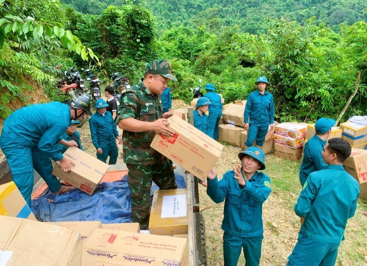 Các lực lượng tham gia bốc dỡ hàng hóa, nhu yếu phẩm, lương thực từ xe đầu kéo xuống điểm tập kết bên đường độc đạo giữa đại ngàn Pù Huống để dùng xe máy chờ vào cho bản làng Na Ngân. Ảnh: TTXVN phát na-ngan3-121025.jpg