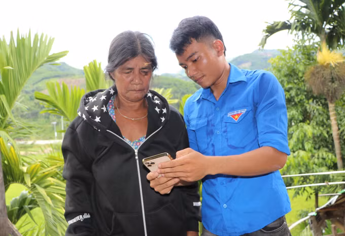 Một đoàn viên thanh niên hướng dẫn người dân sử dụng các ứng dụng truy cập dịch vụ công trực tuyến. Ảnh: Đinh Hương/TTXVN