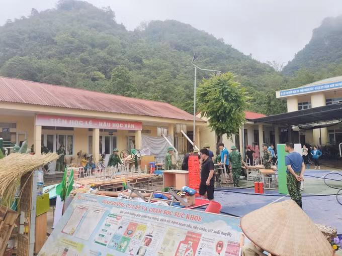 Người dân, lực lượng vũ trang tham gia khắc phục hậu quả sau mưa lớn tại Trường Mầm non và Tiểu học Minh Long. Ảnh: TTXVN phát