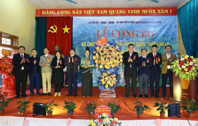 Lãnh đạo huyện Thuận Châu tặng hoa chúc mừng xã Chiềng Pha đạt chuẩn nông thôn mới. Ảnh: Quang Quyết - TTXVN