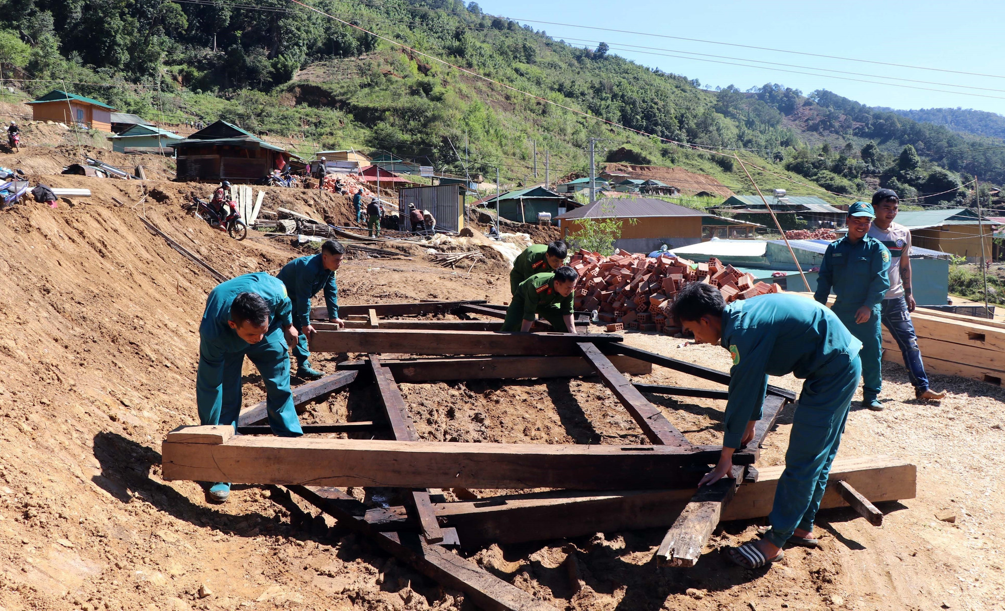 Lực lượng Dân quân, Công an xã Măng Ri cùng người dân đang dựng lại nhà mới giúp dân an cư.