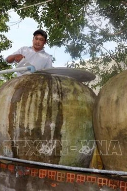 Tranh thủ vào mùa mưa, người dân sinh sống ven biển An Biên tận dụng lu để chứa nước sử dụng. Ảnh: Lê Sen - TTXVN