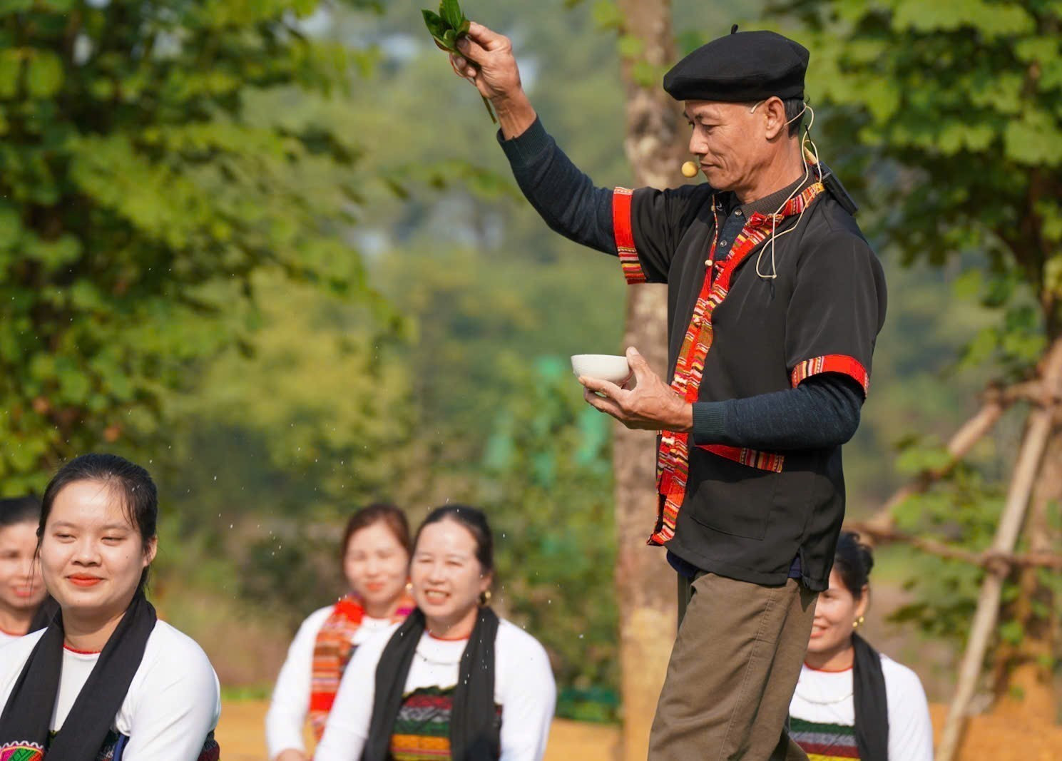 Thầy Mo - chủ lễ - lấy lá tre nhúng vào chén rượu đi vãi xung quanh nhằm xua đi tà ma xấu. Ảnh: Khánh Hoà - TTXVN potal-le-mung-com-moi-cua-dong-bao-thai-tinh-thanh-hoa-7786104.jpg