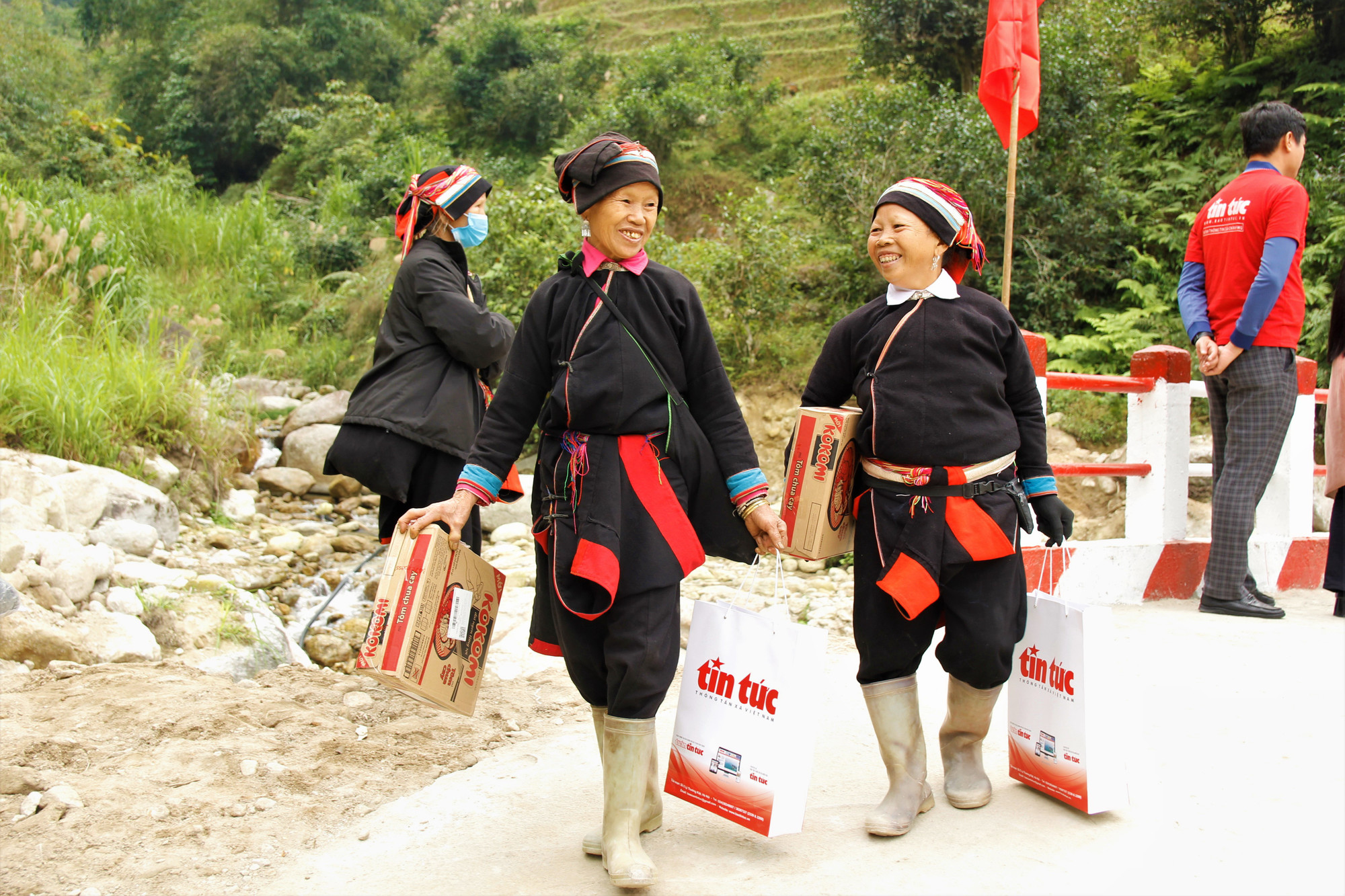 Bà Đặng Thị Nhìn, 70 tuổi (bìa trái) vui mừng khi đi trên cây cầu mới Xín Chải và nhận được nhiều quà tặng từ chương trình "Đồng hành cùng vùng khó". Ảnh: Thế Đoàn chuyendein-05.jpg