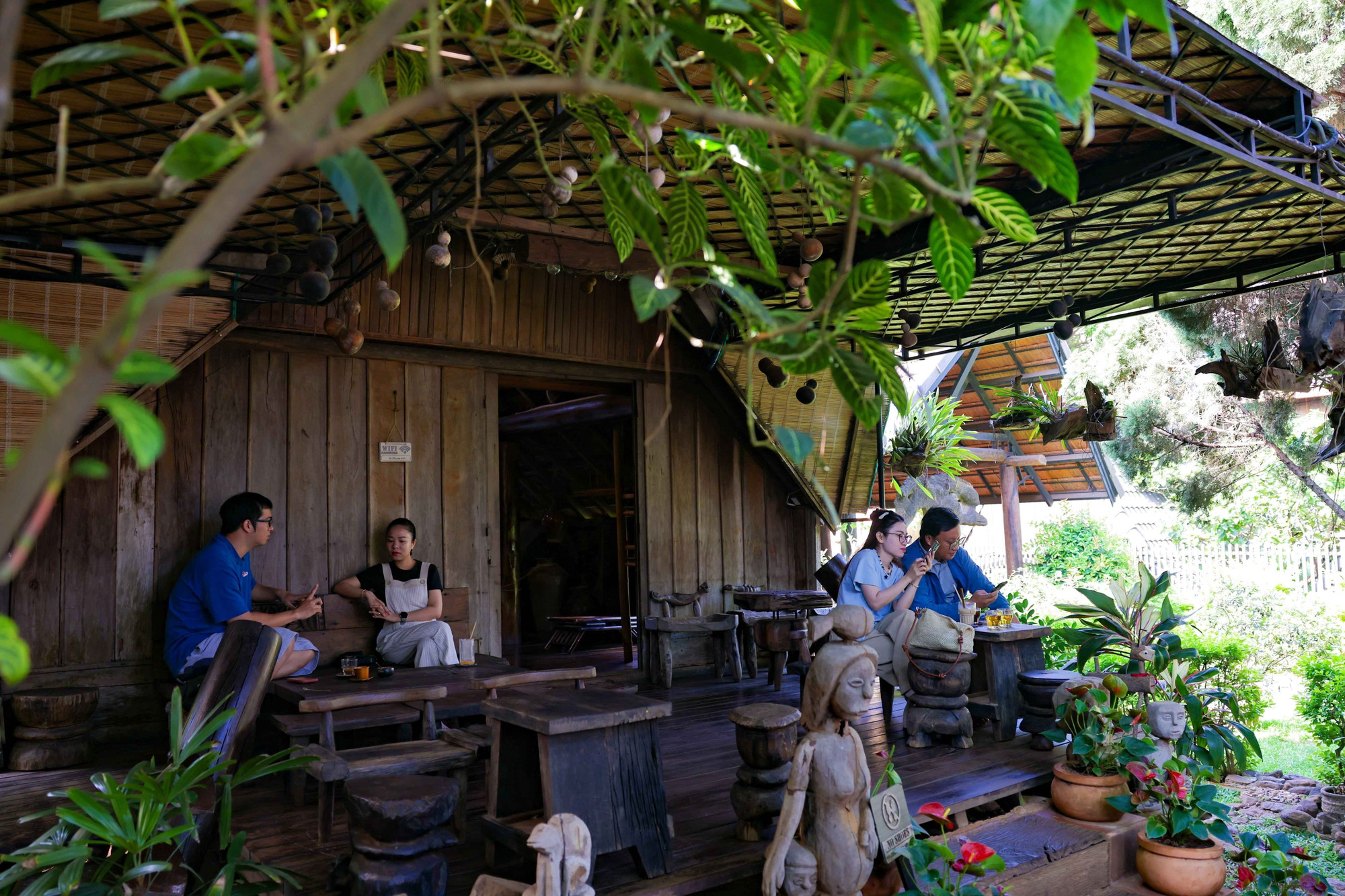 Du khách thưởng thức cà phê giữa khung cảnh yên bình, kiến trúc cổ xưa độc đáo của buôn Akŏ Dhông. Ảnh: Thanh Tùng – TTXVN potal-buon-du-lich-cong-dong-ako-dhong-diem-den-an-tuong-trong-long-buon-ma-thuot-7930824.jpg