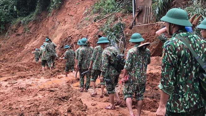 Lực lượng cứu hộ, cứu nạn hành quân tới hiện trường vụ sạt lở trong điều kiện vô cùng khó khăn do đường giao thông có nhiều điểm bị sạt lở nghiêm trọng. Ảnh: Thanh Thủy - TTXVN