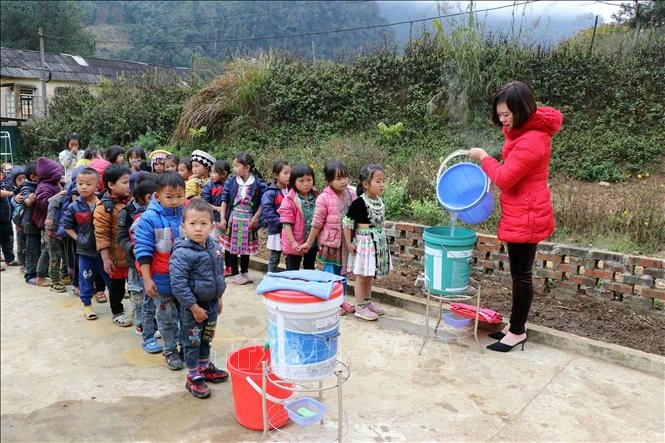 Giáo viên trường Mầm non Bình Minh, xã Co Mạ (Thuận Châu, Sơn La) chuẩn bị nước ấm để học sinh vệ sinh cá nhân. Ảnh: Hữu Quyết - TTXVN