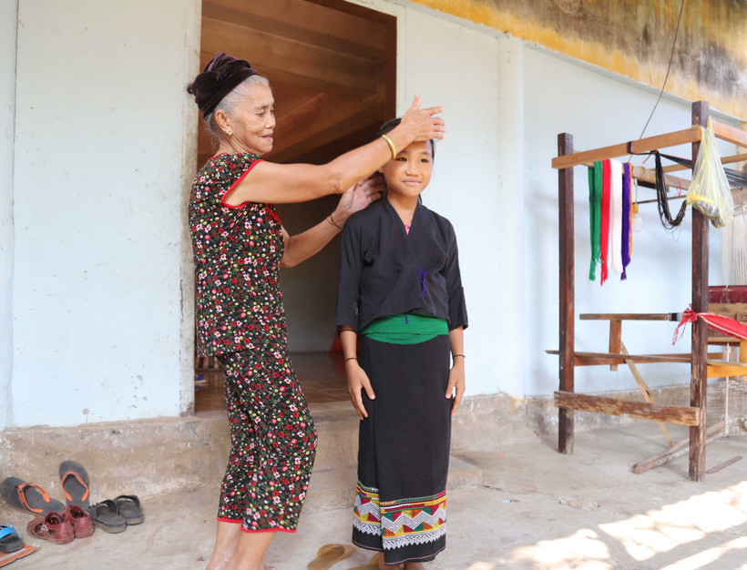 Bà Vi Thị Dung hướng dẫn cách mặc trang phục truyền thống cho thế hệ trẻ. Ảnh: Xuân Tiến - TTXVN