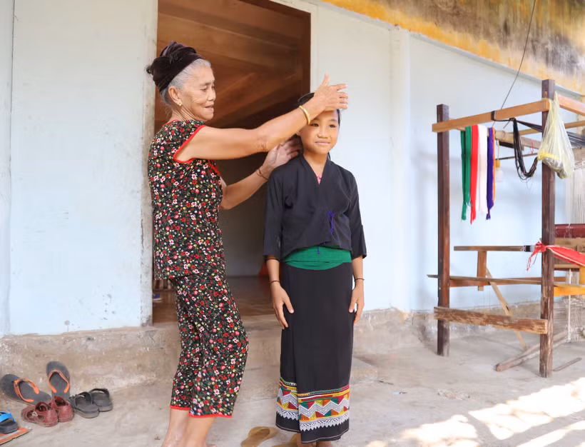 Bà Vi Thị Dung hướng dẫn cách mặc trang phục truyền thống cho thế hệ trẻ. Ảnh: Xuân Tiến - TTXVN