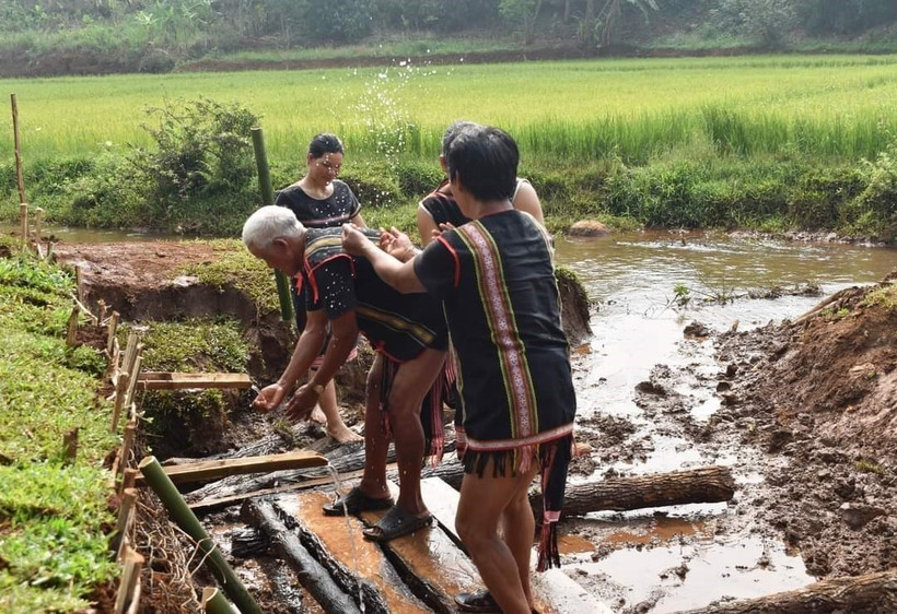 Sau lễ cúng, người dân trong làng cùng xuống giọt nước để thực hiện các nghi thức cầu may mắn. Ảnh: TTXVN phát