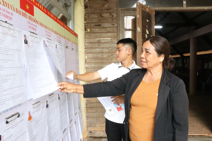 Người dân buôn Kdun, phường Buôn Ma Thuột (tỉnh Đắk Lắk), quan tâm, tìm hiểu tiểu sử tóm tắt của các ứng cử viên.