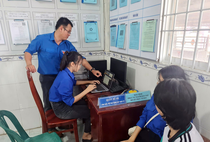 Anh Nguyễn Minh Thái, Phó Chủ tịch Ủy ban Mặt trận Tổ quốc, Bí thư Đoàn xã Tân Tiến hướng dẫn đoàn viên thanh niên các bước hỗ trợ người dân tiếp cận dịch vụ công trực tuyến. Ảnh: TTXVN phát ca-mau-2.jpg