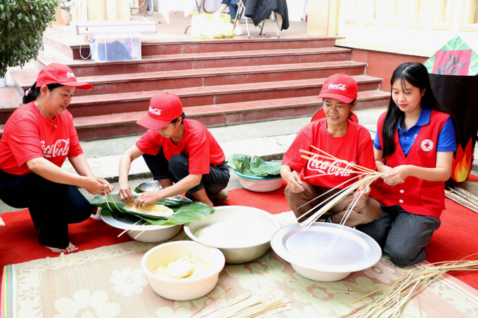 Cán bộ, hội viên Hội Chữ thập đỏ và đại diện nhà tài trợ Coca-Cola Việt Nam cùng người dân địa phương tham gia gói bánh chưng tại Chương trình. Ảnh: Thu Hằng/TTXVN
