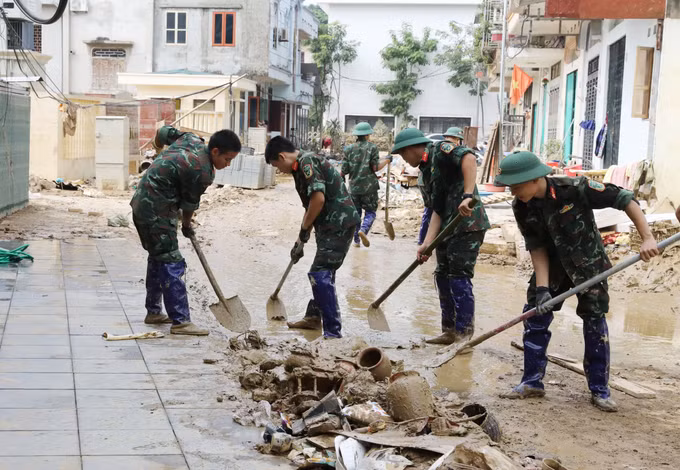 Các chiến sĩ Quân đội dọn dẹp bùn đất, vệ sinh môi trường sau mưa lũ trên phố Nhị Quỹ, phường Phan Đình Phùng.