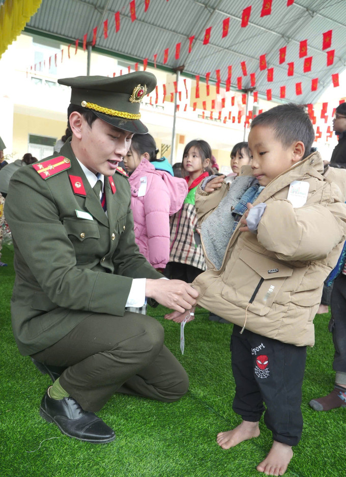 Cán bộ, chiến sĩ phòng Tham mưu Công an tỉnh Tuyên Quang mặc áo ấm cho học sinh trường Mầm non Bản Máy, tỉnh Tuyên Quang.