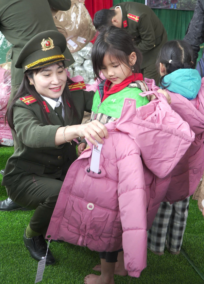 Cán bộ, chiến sĩ phòng Tham mưu Công an tỉnh Tuyên Quang mặc áo ấm cho học sinh trường Mầm non Bản Máy, tỉnh Tuyên Quang.