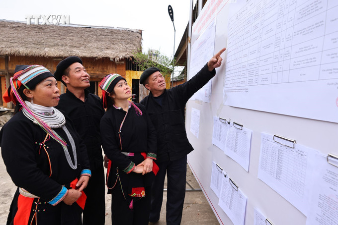 Cử tri xem danh sách đại biểu ứng cử được niêm yết công khai tại nhà văn hóa thôn Nặm Đăm, xã Quản Bạ. Ảnh: Minh Đức/TTXVN
