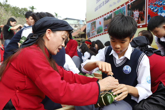 Nghệ nhân hướng dẫn học sinh các thao tác gói bánh, qua đó giúp các em trải nghiệm thực hành di sản, hiểu hơn giá trị văn hóa truyền thống gắn với đời sống cộng đồng.