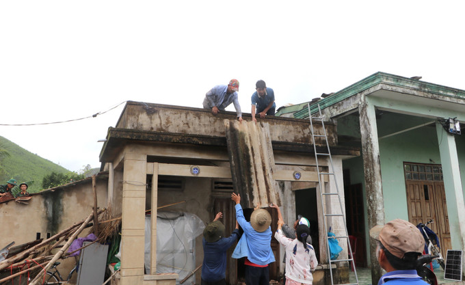 Người dân giúp nhau lợp lại nhà sau lốc xoáy.