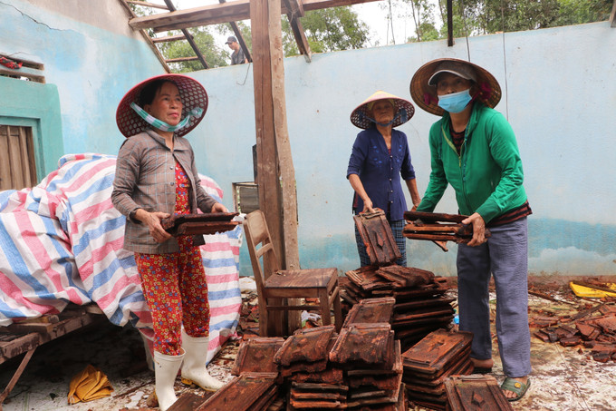 Người dân hỗ trợ nhau dọn dẹp đống đổ nát, lợp lại mái nhà sau trận lốc xoáy.
