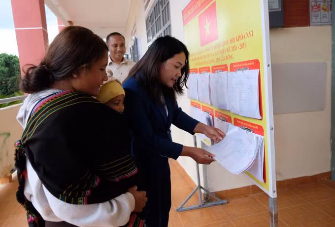 Chị Dà Ju K’Kim (thôn Long Lanh) được cán bộ xã Lạc Dương hỗ trợ kiểm tra thông tin của vợ chồng chị trong danh sách cử tri niêm yết tại UBND xã Lạc Dương.