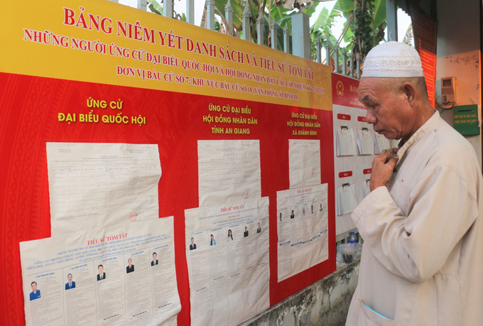 Ông Sale’s (ấp Bình Di, xã Khánh Bính, tỉnh An Giang) đối chiếu lại thông tinh những người ứng cử đại biểu Quốc hội khóa XVI và đại biểu HĐND các cấp trước khi vào thực hiện quyền công dân của mình. Ảnh: Công Mạo/TTXVN