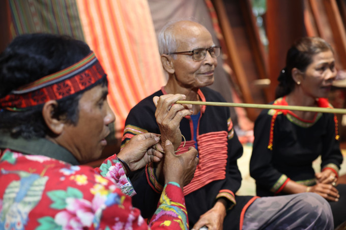 Thầy cúng thực hiện nghi lễ đeo vòng tay cầu sức khỏe cho gia chủ.