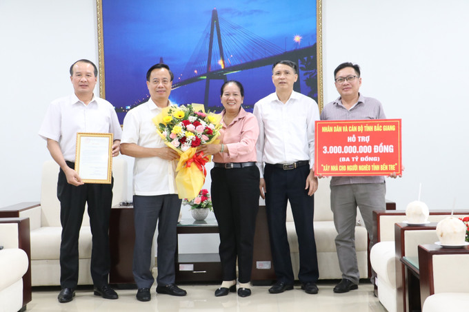 Phó Chủ tịch Ủy ban MTTQ Việt Nam tỉnh Bến Tre Đặng Thị Phượng tiếp nhận kinh phí xây dựng 50 căn nhà Đại Đoàn kết và trao hoa, thư cảm ơn cho Ủy ban MTTQ Việt Nam tỉnh Bắc Giang. bac-giang-ho-tro-ben-tre-3.jpg