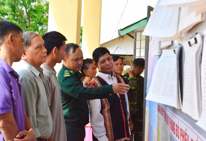 Cán bộ Đồn biên phòng xã Ia Nan cùng già làng hướng dẫn người dân tìm hiểu thông tin của các ứng cử viên đại biểu Quốc hội, HĐND các cấp tại điểm bầu cử ở làng Sơn, xã Ia Nan.