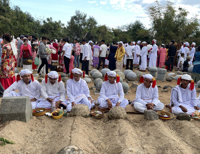 Con, cháu dòng tộc mặc bộ áo truyền thống thực hiện nghi lễ tảo mộ, mời tổ tiên về chung vui Tết Ramưvan.