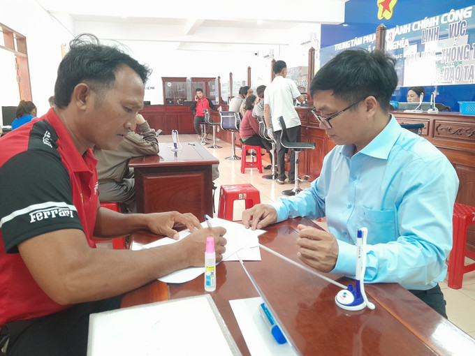 Ông Phạm Văn Tuấn, Phó Giám đốc chuyên trách Trung tâm phục vụ Hành chính công xã Phú Nghĩa, trực tiếp hướng dẫn người dân thực hiện thủ tục hành chính. dong-bao-su-dung-cong-nghe-1.jpg