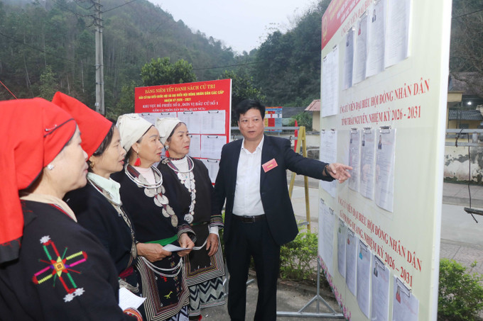 Cán bộ UBND xã Phong Quang phụ trách khu vực bầu cử đang hướng dẫn người dân về thủ tục bầu cử. Ảnh: Vũ Hoàng Giang/TTXVN